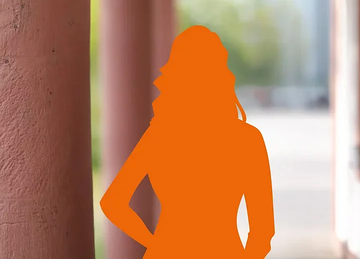 Eine orangefarbene Silhouette einer Frau steht vor Säulen und einem unscharfen Hintergrund im Freien.