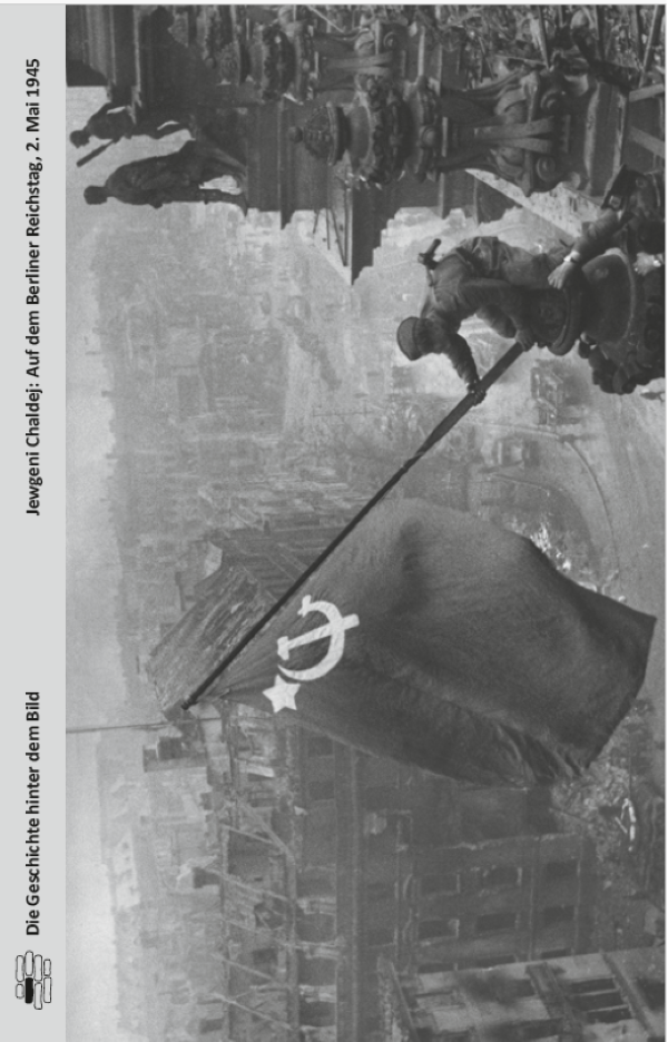 Ein sowjetischer Soldat hisst die Flagge der UdSSR über dem beschädigten Reichstagsgebäude in Berlin während des Zweiten Weltkriegs, Mai 1945.