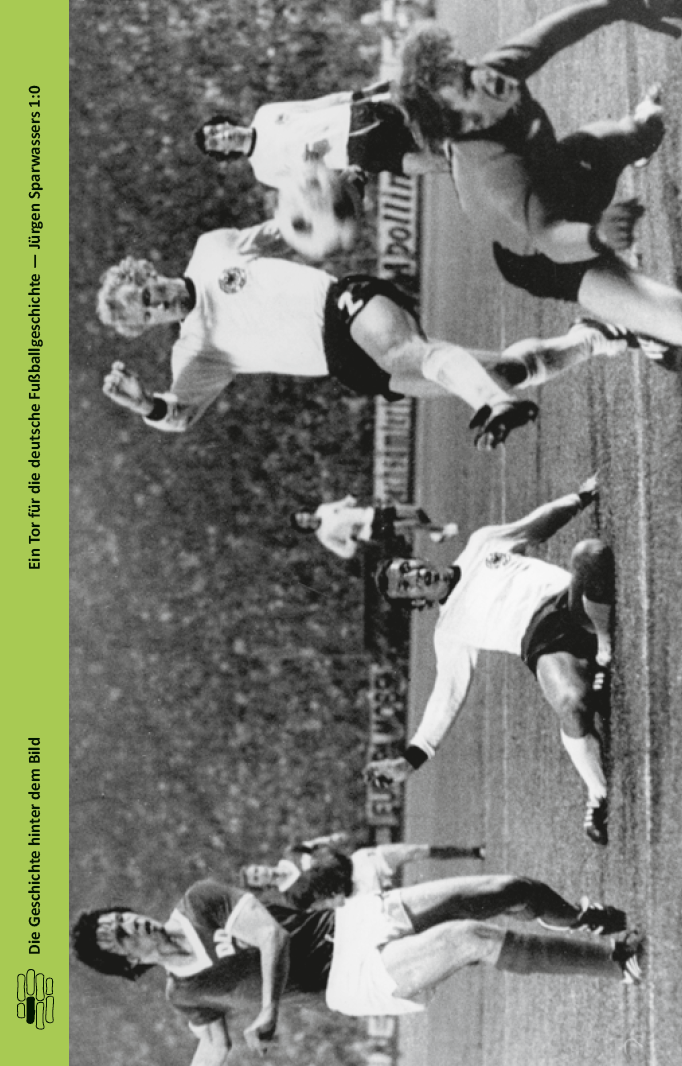 Eine Schwarz-Weiß-Aufnahme eines Fußballspiels zeigt einen deutschen Spieler, der hoch über einen Torwart springt, während andere Spieler zusehen. Das Bild ist seitlich gedreht und enthält eine grüne Seitenleiste mit deutschem Text auf der linken Seite.