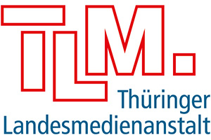Logo der Thüringer Landesmedienanstalt (TLM), mit fetten roten Buchstaben "TLM." über dem blauen Text "Thüringer Landesmedienanstalt" auf weißem Hintergrund.