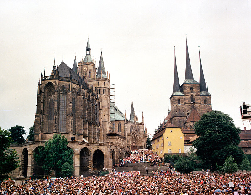 An einem bewölkten Tag versammelt sich eine große Menschenmenge vor dem Erfurter Dom.