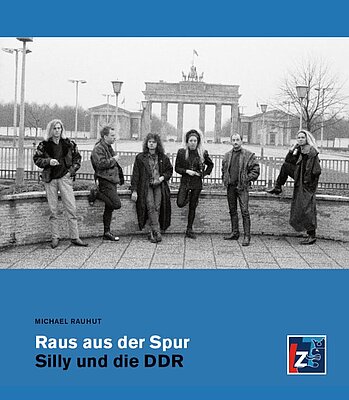 Fünf Personen posieren vor dem Brandenburger Tor in Berlin auf dem Cover des Buches "Raus aus der Spur: Silly und die DDR" von Michael Rauhut.