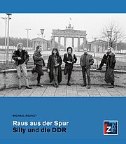 Fünf Personen posieren vor dem Brandenburger Tor in Berlin auf dem Cover des Buches "Raus aus der Spur: Silly und die DDR" von Michael Rauhut.
