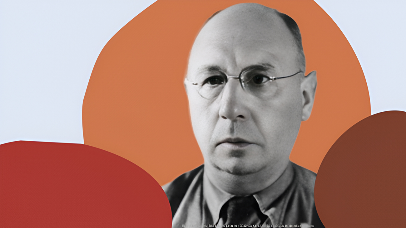 Ein glatzköpfiger Mann mit einer runden Brille und einem Hemd ist vor einem abstrakten Hintergrund mit roten und orangefarbenen Formen zu sehen.